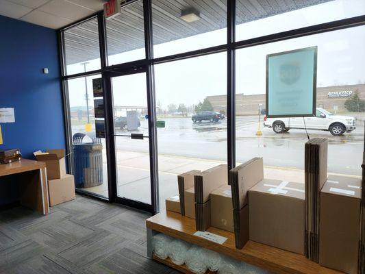 Shelf with boxes and packing materials, front door, and windows.