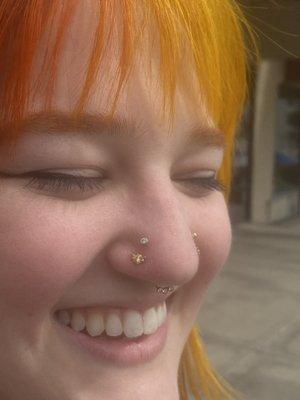 High and low paired nostril piercings with 14k gold bees and CZ bezels