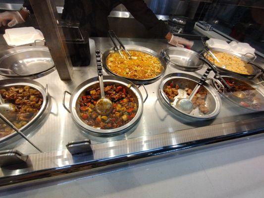 The orange chicken on the right is almost gone, and the bin of vegetables is empty, between the chow mein and fried rice