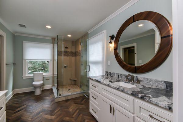 Beautiful guest bathroom with River White granite countertops, white custom cabinetry. The floor is a wood-look tile in a her...