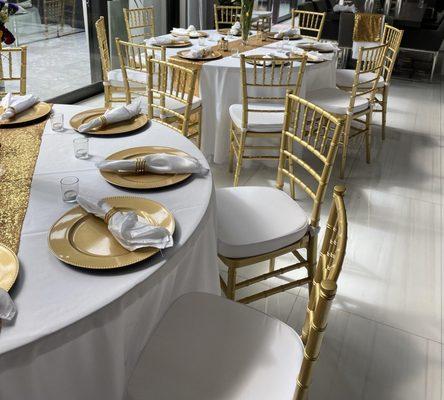 Guest Table Setup with White Linen and napkins, Sequen  Gold Table Runner, Gold Chiavari Chairs