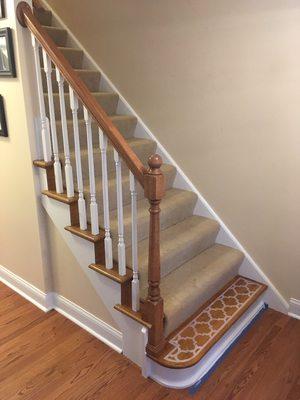 Iron rails replaced with oak, and oak starting step repaired and decorative finish done on tread to match living room carpet.