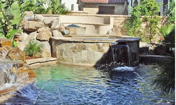 Natural stone used around pool and spa created a secluded spa and firepit area.  This works well in a small backyard.