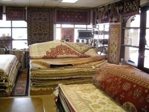 Inside the store. Stacks of rugs to go through, great designs, high quality, all different sizes and colors.