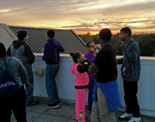 Middle school students observing partial solar eclipse from planetarium Observation Deck