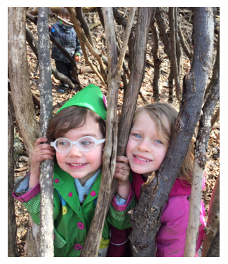 Two preschool students playing and learning in the wooded area behind our school.