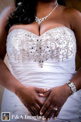 African-American bride in a elegant poes showing off the details of her dress