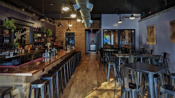 View of the interior of the tasting room featuring bar seating and high-top table seating.