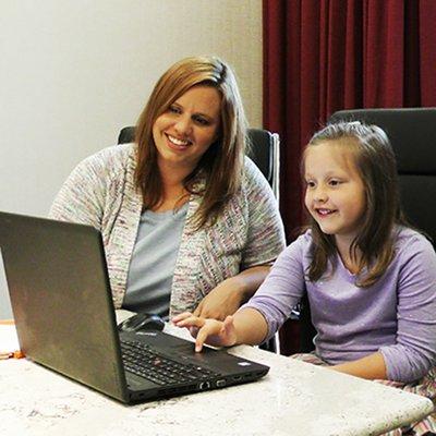 Parent and child using a laptop computer to access virtual school lessons