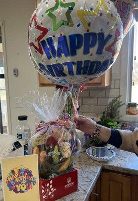 The edible arrangement birthday celebration  fruit and some pieces dipped in semi sweet chocolate and 3 balloons