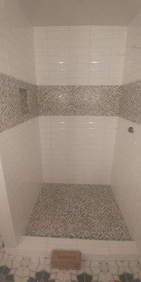 Master shower with glass deco stripe and shower pan.