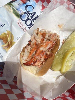 Lobster roll, all rolls served cold. We got this with warm butter.  Picture after a few bites.  Pickle and chips on the side.