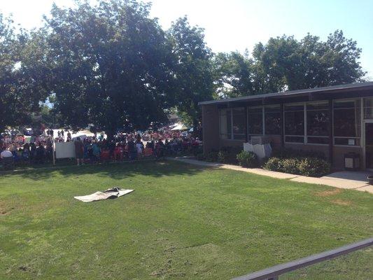 Lots of people sitting along the churches education building as they watch the parade.