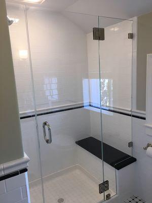 Frameless shower hinges off panel with bench seat