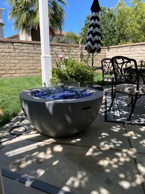 Propane fire pit (refinished), fire glass (3 bags), glass wind screen, umbrella, rolling umbrella base, poolside umbrella table.