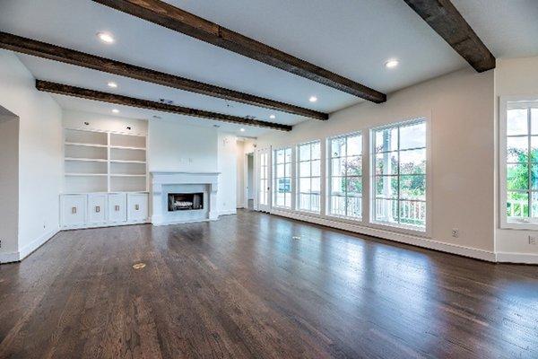 Open concept living room that opens up to kitchen and dining area. Custom gas fireplace with marble surround and custom built-ins.