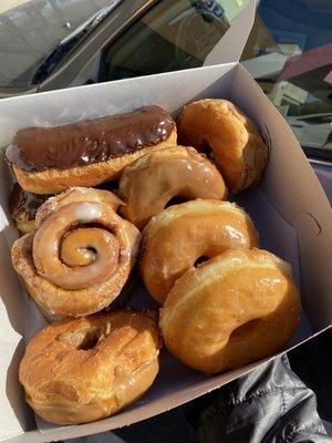 An assortment of maple, glaze, chocolate donuts and a cinnamon roll.