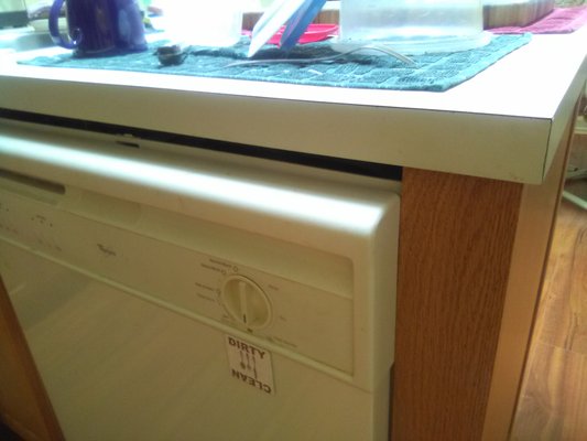 Extremely awful job of fitting the dishwasher into  it's space in the repaired kitchen counter.