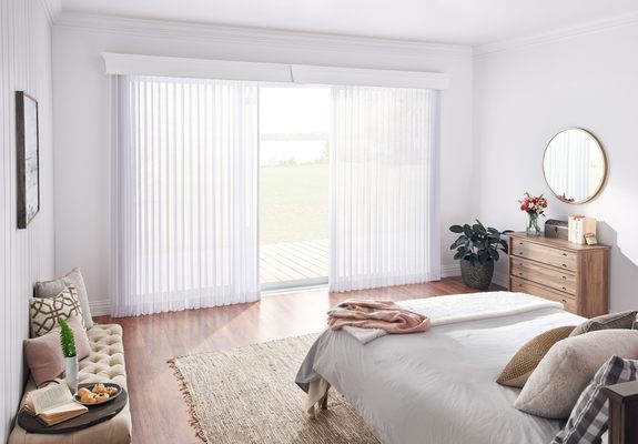 Sheer traverse drapes with wooden cornice in bedroom.