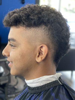 Burst Fade (Youth) with a disconnect to curly hair and leave the top to grow .