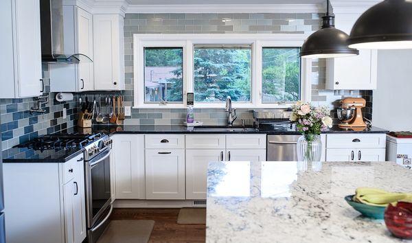 Natural lighting galor! Shaker white cabinets, with backsplash tile surrounding the window.