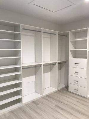 Walk-in closet in white melamine with lots of hanging, shelves and drawers.