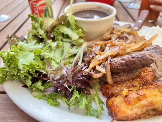 Bistec plate with salad, plantains and black beans