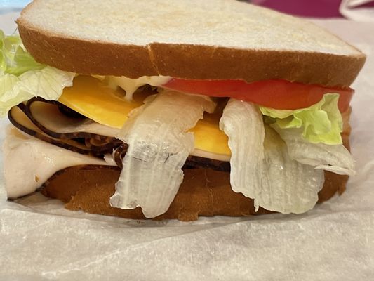 Turkey sandwich with mayonnaise, lettuce, tomato and Colby cheese.