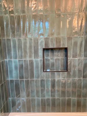 Vertical tile on the shower with a built-in niche and Schlueter metal trim.