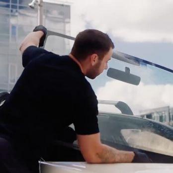 Technician installing a windshield on a vehicle.