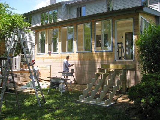 Stairs being built and cedar siding being stained.