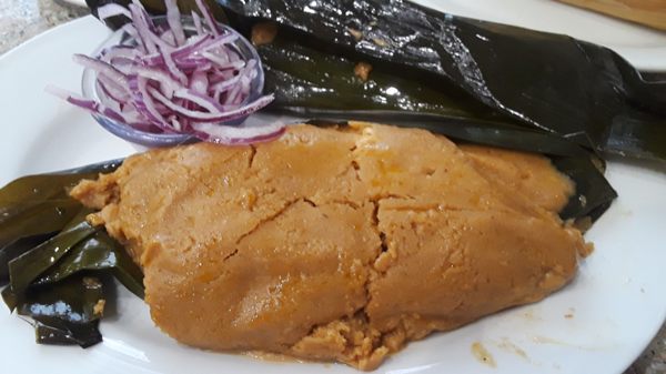 Bollo de Pescado: Green plantain tamale filled w/ fish, peanut butter, herbs, & spices wrapped in banana leaf