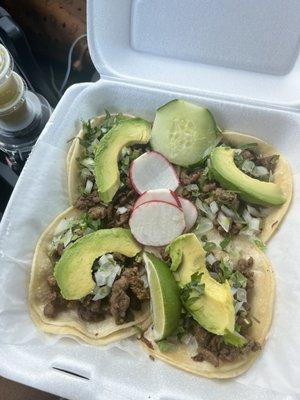 4 steak tacos with onion, cilantro, and avocado.