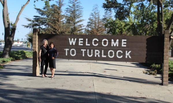 Loan officers next to welcome to Turlock sign