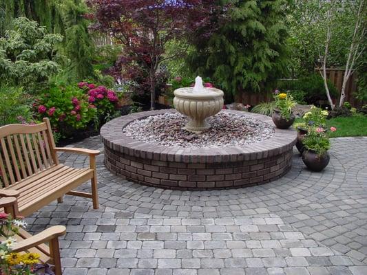 Bubbling urn, raised brick fountain with a paver patio.