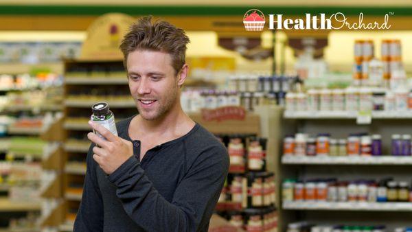 Men shopping for supplements with Health Orchard logo in background.