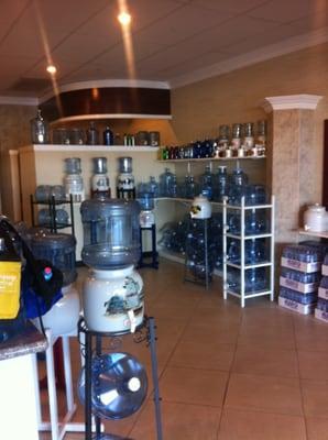 Inside the store to the right of the counter. Water containers of all sizes for sale.