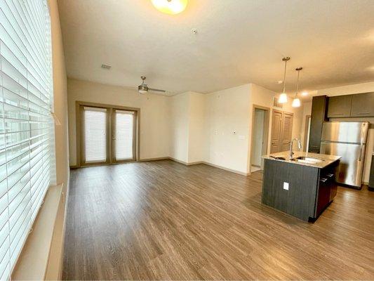 Apartment tour - entry area looking into living room and kitchen. Plank flooring goes throughout the apartment with carpet in the bedrooms.