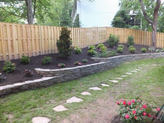 TreeStone Landscaping tiered garden with stone wall and paver walkway.