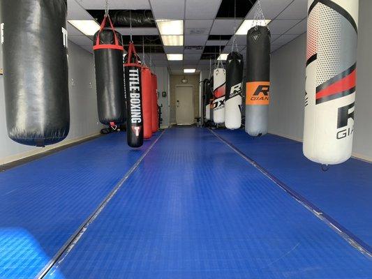 Inside of the gym. Picture of martial arts mats, boxing and kickboxing bags.