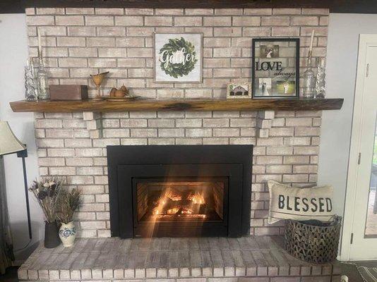 Custom live edge mantle and whitewashed fireplace bricks