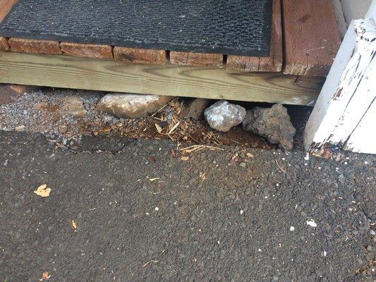 Holes covered by rocks to  prevent rats from going under.