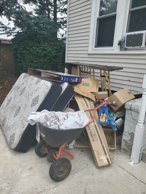 Piles of junk fester in front of building for over a month.