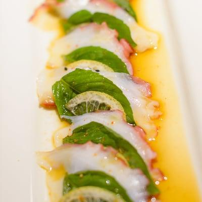 Octopus sashimi with fresh basil, thinly sliced lemon and ponzu sauce.