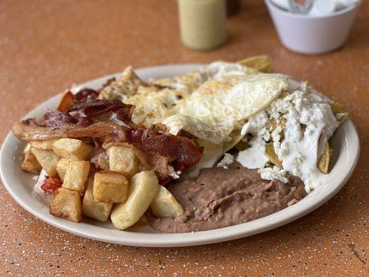 Mixed chilequiles plate with over easy eggs and side of bacon.