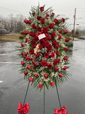 Standing spray with all red roses and baby's breath.