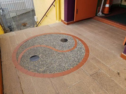 Ying & Yang symbol outside outside of main doorway, atop short flight of steps.