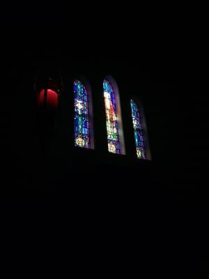 Close-up of everlasting candle and stained glass above the altar.