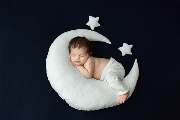 Newborn Portrait of baby boy laying on moon with stars.