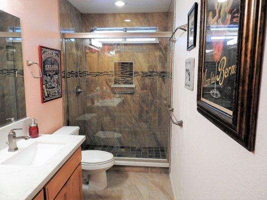 Bathroom remodel done with porcelain tile and decorative backsplash.